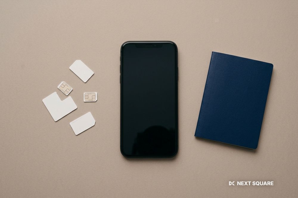 伏せて置いたスマートフォンと、端に寄せた無地のSIMカードのイメージ
