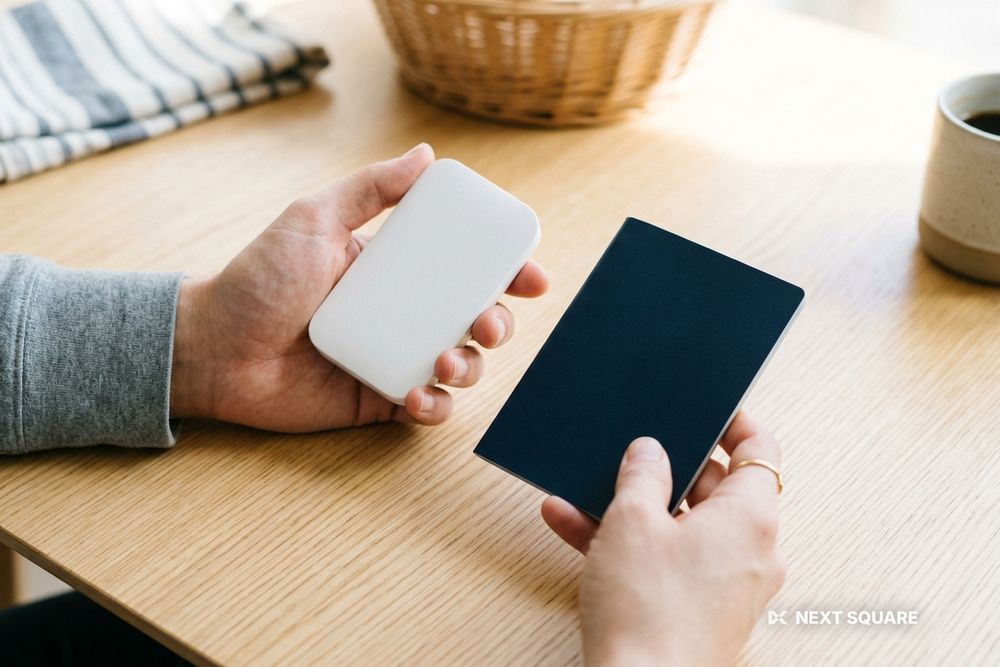 テーブルの上でポケットWiFiルーターとパスポートを手に持ったイメージ